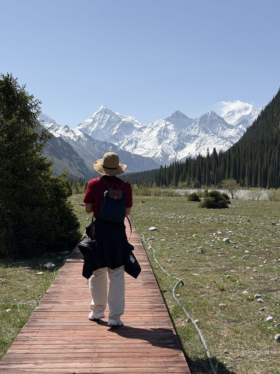 Jimmy walking a boardwalk toward snow-capped mountains