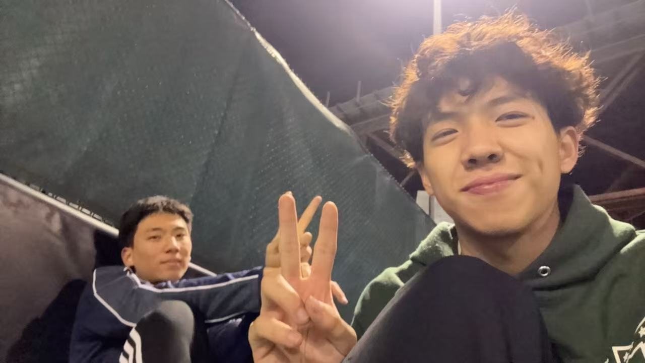 Jimmy flashing a peace sign beside a friend on a tennis court at night