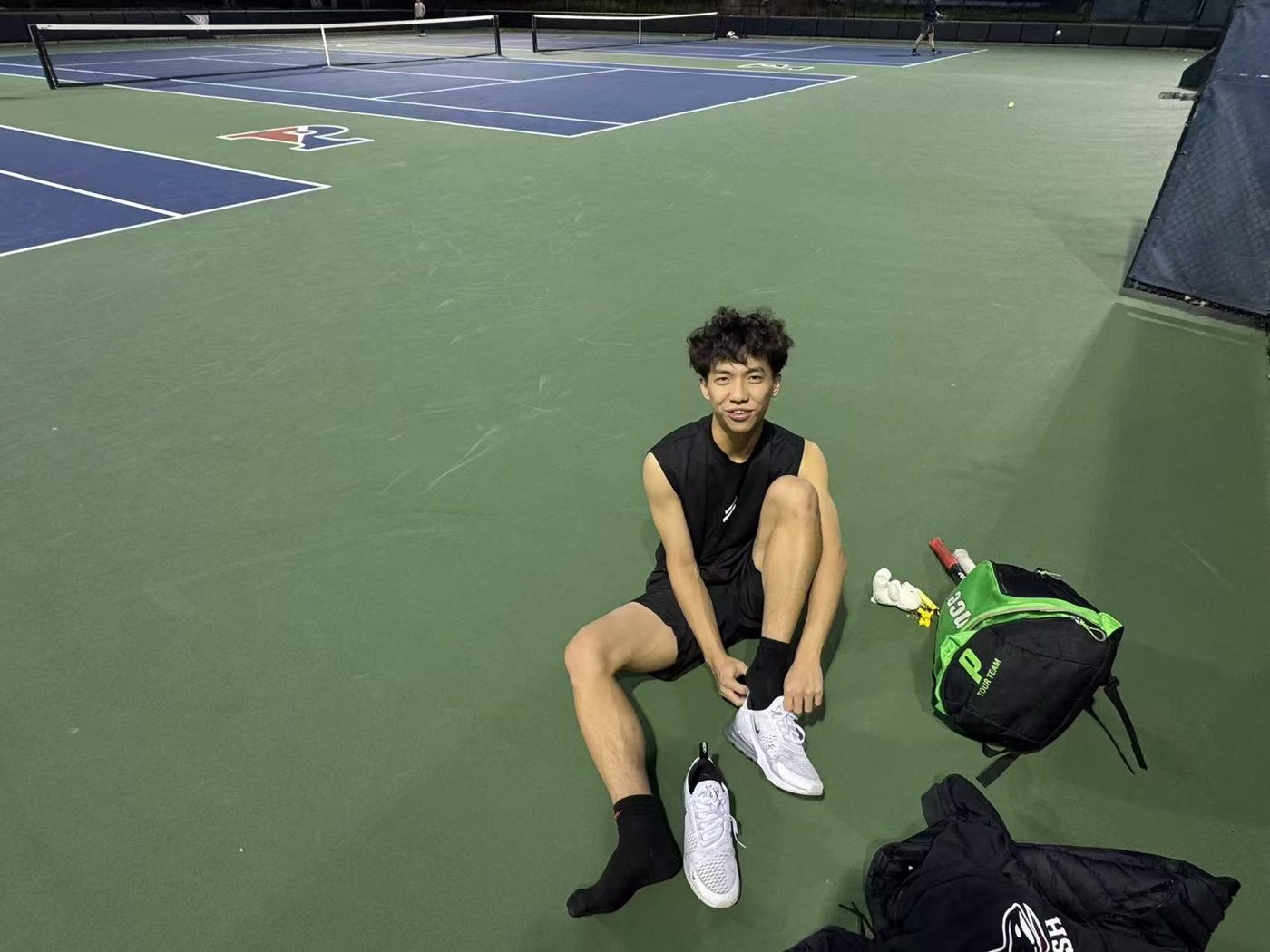 Jimmy sitting on a tennis court at Penn after a session